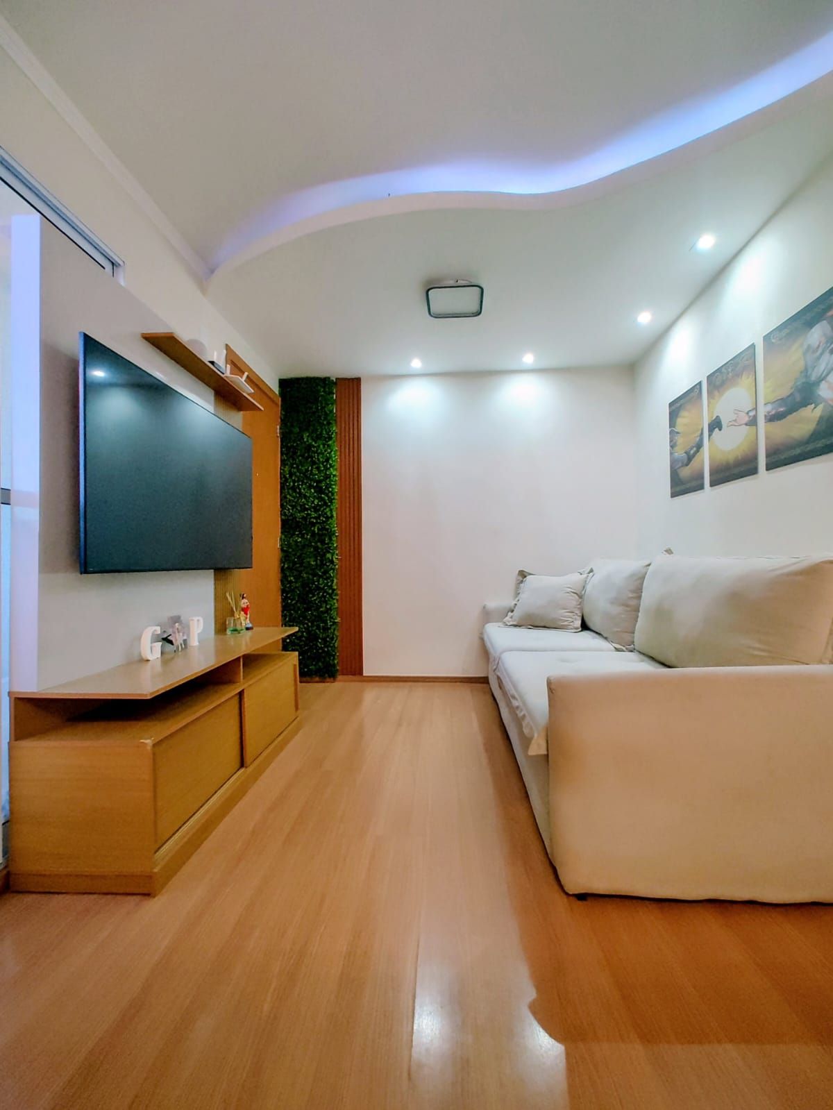 Sala de estar do apartamento à venda no Monte Blanc, em São Carlos, com sofá, painel de TV e piso laminado
